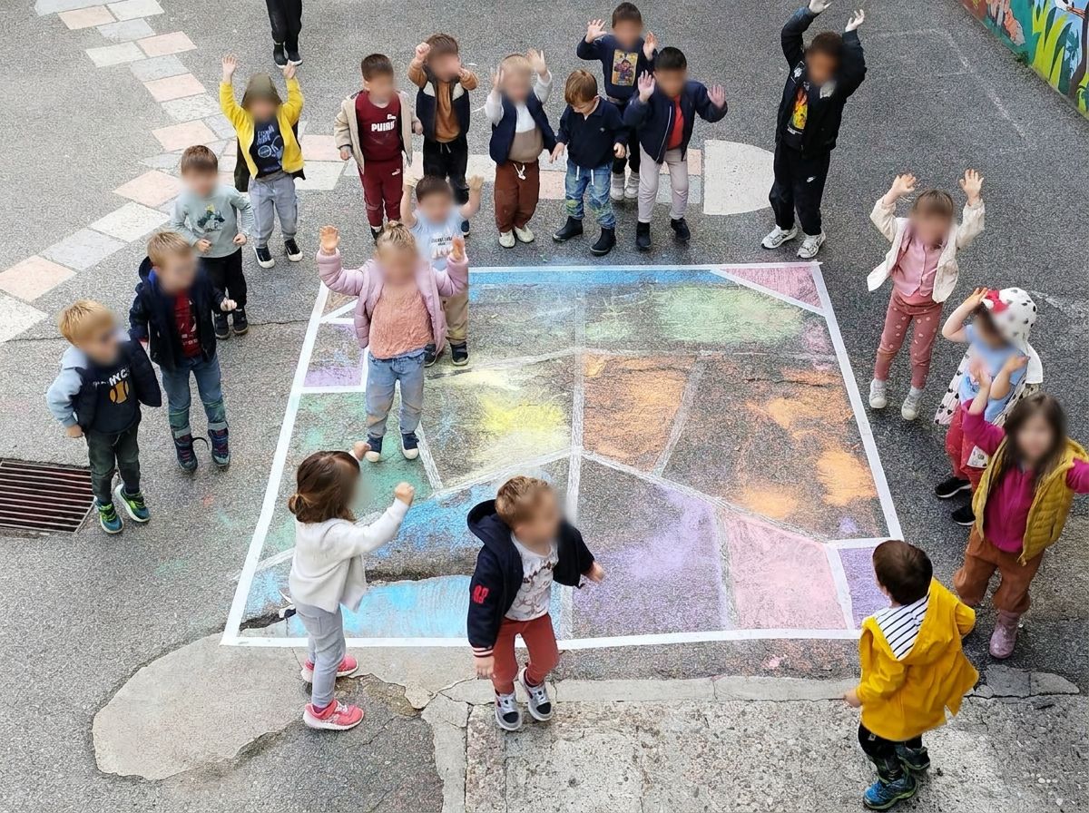 Les enfants rassemblés autour de grands dessins à la craie dans la cour
